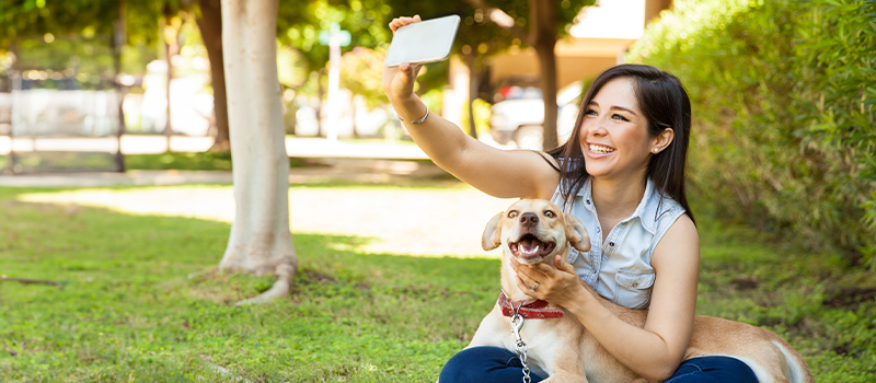 Lady Holding Phone And Taking Selfie of Her and Dog She is Walking